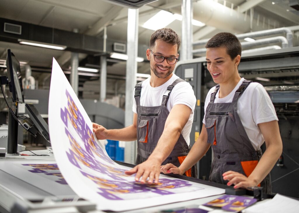 Graphic engineers or workers checking imprint quality in modern print shop.